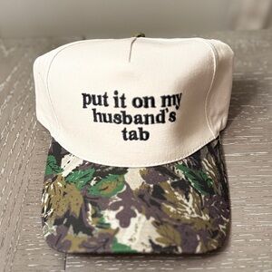 Put It On My Husband’s Tab Trucker Hat Crean & Black Embroidered Graphic Camo